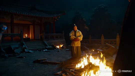夜幕下，一座古老的中国清朝风格建筑的后院，火光摇曳。地面上杂物凌乱，仿佛经历过一场争斗。在这阴暗而神秘的氛围中，一个身着清朝服饰的僵尸突然出现，动作僵硬而诡异。它的眼睛闪烁着幽蓝的光芒，与周围的黑暗形成鲜明对比。此时，一位持剑的道士在后院起火作坛，火光映照出他严肃而坚定的面容。道士与僵尸之间的气氛紧张而恐怖，仿佛有一场超自然的对决即将展开。整个场景细节丰富，阴影对比强烈，充满了阴森恐怖和神秘诡异的氛围。 by Hailuo AI Video Generator