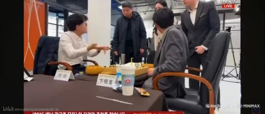 左侧坐着的男子抓起棋盘砸右侧坐着的男子的头 右侧坐着的男子倒地 by Hailuo AI Video Generator