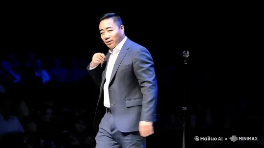 舞台上，灯光唰地一下聚焦，一个身着休闲西装的年轻人，脚步轻快，“哒哒”地从舞台一侧迈到正中央。他站定，嘴角一勾，露出自信的笑容，微微抬起下巴，目光扫视全场，与观众们一一对视，那眼神里满是热情与亲切，引得台下瞬间安静下来。
 
他不慌不忙地抬起手，整了整领口，轻轻清了清嗓子，那动作看似随意，却透着十足的沉稳。接着，他一只手自然地垂在身侧，另一只手在空中虚晃了一下，像是在抓住大家的注意力，随后，脱口秀正式开场。说话间，他的身体随着节奏微微晃动，讲到有趣处，肩膀微微耸起，眼睛眯成一条缝，脸上的笑意都快溢出来，还时不时用手指在空中比划着，加强语气，台下观众的笑声和掌声此起彼伏 。 by Hailuo AI Video Generator