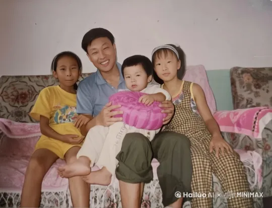 照片中的大人和小孩在有说有笑的聊天玩闹，大人怀里抱着的小男孩从怀里站到地上，走向镜头拿手捂镜头。 by Hailuo AI Video Generator