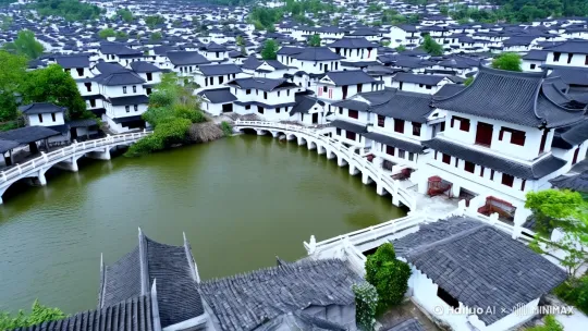 这段视频通过细腻的镜头语言和优美的画面，成功地将观众带入了一个充满江南水乡韵味的古色古香的庭院。视频开头以缓慢的航拍镜头展示了江南水乡的整体美景，小桥流水、白墙黛瓦的建筑错落有致，营造出一种宁静和谐的氛围。

镜头缓缓推进，进入庭院，中央的木制亭子成为焦点。亭子的雕梁画栋充满了历史的韵味，木窗的设计独具匠心，圆形窗框仿佛是一幅天然的画框，将窗外的美景定格其中。随着镜头的推进，窗内出现了两个人，他们微笑着看向镜头，仿佛在与观众互动。这种互动感增强了观众的代入感，让人感觉自己也置身于这个美丽的庭院中。

镜头继续推进，逐渐拉近两人的距离。此时，背景中的红灯笼和雕刻精美的木柱逐渐清晰，增添了画面的层次感和立体感。窗外的庭院景色也变得更加清晰，可以看到绿树成荫，小桥流水，仿佛置身于一幅水墨画中。这种细腻的镜头语言和优美的画面让人仿佛置身于江南水乡，感受那份宁静与美好。

视频的最后，镜头定格在两人的微笑上，画面渐渐淡出，留下“初春快乐”的祝福语。这一祝福语不仅点明了视频的主题，也为观众带来了温馨的感受。整个视频充满了柔美的意境，让人仿佛置身于江南水乡，感受那份宁静与美好。通过这些细腻的镜头语言和优美的画面，视频成功地传达了江南水乡的独特魅力和宁静氛围，让人回味无穷。 by Hailuo AI Video Generator
