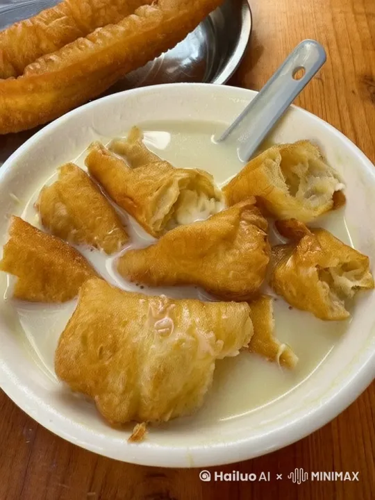 我右手拿起碗中的汤勺慢慢搅动碗中的豆浆，碗里泡着几块油条，油条随着搅动的力道而在碗中上下左右浮动。 by Hailuo AI Video Generator