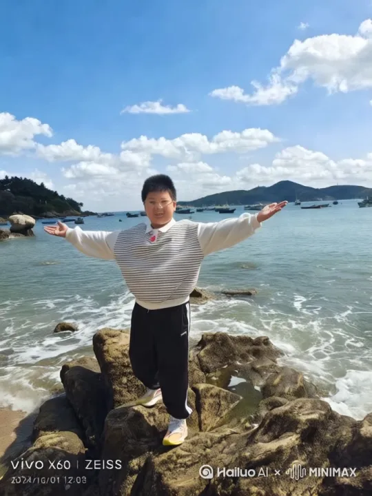 阳光男孩站在海边礁石,手持黑色话筒,唱歌时眉眼舒展,嘴角扬起灿烂笑容,眼里溢满愉悦。双臂随节奏轻摆,身体自然晃动,与海浪韵律呼应。偶尔轻晃脑袋,发丝随海风微动。时而闭眼沉浸,时而望向前方,神态松弛自在,歌声仿佛融入碧海蓝天,尽显少年随性与对歌唱的投入,周身洋溢自由快乐的气息。电影运镜左移推近,大师级 by Hailuo AI Video Generator