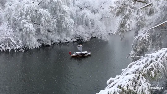 无人机视角，大雪漫天江上小船，船上站一灰衣女子在跳舞，两岸树木堆满了积雪，大雪飘落在平静水面，白色色调，中式意境，宁静氛围 。左移，右摇 by Hailuo AI Video Generator