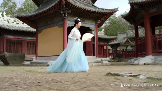 画面中，身着华丽飘逸古风服饰、妆容精致宛如仙子的[右移,跟随]美女，手持一把古风团扇，轻盈地漫步在古色古香的亭台楼阁间。突然，她被脚下一块不起眼的石头狠狠绊了一下，整个人以夸张的姿势向前扑出，手中的团扇像断了线的风筝一样飞了出去，脸上原本优雅的神情瞬间变成了惊恐和滑稽的扭曲模样。 by Hailuo AI Video Generator