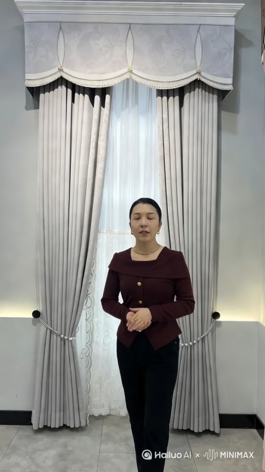 画面静止，展示她站在窗帘前的全身照。她右手提着包，左手轻轻放在胸前。
背景音乐轻柔，营造温馨氛围。
画外音：
"今天我们来介绍一款独特的手提包。"

镜头切换：

特写镜头，展示手提包的细节。包上的复杂图案清晰可见，可以是花纹或几何图案。
镜头慢慢移动，展示包的各个角度，包括包的顶部、底部和侧面。
画外音：
"这款手提包采用了精美的图案设计，充满了复古和优雅的气息。材质看起来非常耐用，适合日常使用。"

镜头切换：

中景镜头，展示她提着包，稍微转身，展示包的背面和侧面。
她开始原地踏步走，保持微笑，展示包的动态效果。
画外音：
"无论是搭配休闲装还是正式场合，这款包都能为你的整体造型增色不少。现在，让我们来看看它的实际使用效果。"

镜头切换：

她继续原地踏步走，镜头跟随她的动作，保持稳定。
镜头慢慢拉远，展示她全身和背景的整体效果。
画外音：
"这款手提包不仅实用，而且时尚，是你日常出行的不二选择。感谢观看，我们下次再见！"

结尾镜头：

画面静止，回到她最初的姿势，展示包的正面。
背景音乐渐弱，视频结束。 by Hailuo AI Video Generator
