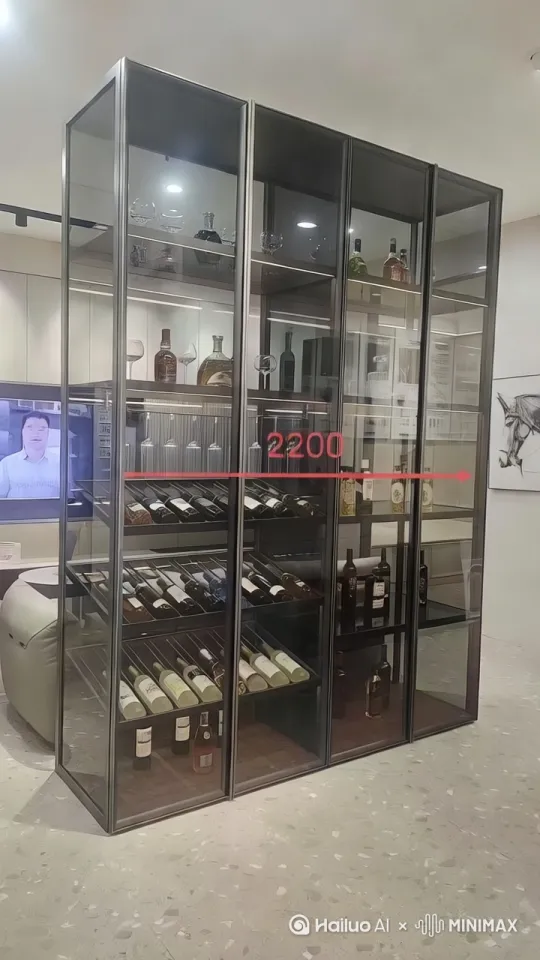 场景描述：高档室内空间内透明酒柜爆开蓝金色能量波纹，浅色石材地面随巨人脚步裂开特效。主体描述：20米高玻璃材质机械酒瓶巨人，液态酒液在透明躯干动态流动，琥珀色眼部光效配合拟人化欢快表情，红酒瓶组成的手臂挥舞霓虹轨迹，威士忌酒液如火焰在机械关节处燃烧。动作描述：酒柜门爆开瞬间巨人拔地而起，踏步行进时地面石材碎裂，香槟瓶左手指尖迸发金色魔法星芒，弯腰时露出躯干内旋转的葡萄酒漩涡核心。视觉风格：机械感透明材质结合液态流动特效，霓虹光轨与动态光影折射。氛围：奇幻科技感与欢快情绪交织，保留高档环境的同时强化能量冲击波细节。技术细节：运镜包含特写快速拉升、低角度仰拍巨人脚步、环绕拍摄魔法星芒迸发，关键帧第3秒酒柜爆破特写，第8秒葡萄酒漩涡核心旋转镜头。[左移,推进,右摇] by Hailuo AI Video Generator