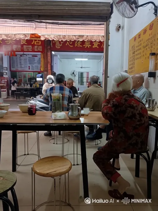 镜头移动，动态跟随，老奶奶猛吸一口烟，喷出浓浓的白烟后，突然和前面的老爷爷打起来，两人实战中国功夫，拳打脚踢，你来我往，把小食店的东西打得到处乱飞，动作自然流畅 by Hailuo AI Video Generator