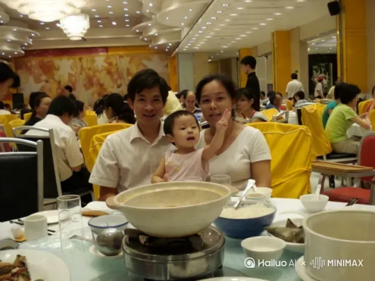 把照片中一家人放大聚焦，去掉周边多余画面，小孩抬手抚摸父母的脸，形成5秒小视频效果，旁边：幸福的一家人。 by Hailuo AI Video Generator