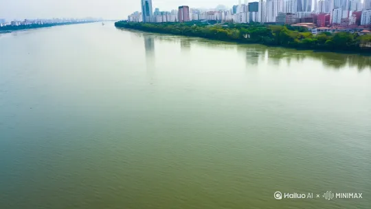 需求：生成无人机航拍拍摄视频，呈现从汉江飞行，穿越后聚焦樊城区清河路与前进路交汇路口标识的画面
 
- 画面描述：以汉江为起始场景，俯瞰从江面略过，镜头向前推进，穿越空间后，精准抵达樊城区清河路和前进路的交汇区域，最后聚焦在路口的标识牌上，清晰展现路口位置信息
​
- 运镜要求：镜头先沿汉江平稳推进，接着快速穿越过渡场景（可模糊化处理 ），最后缓移并精准聚焦交汇路口标识（前进路和清河路交叉口），运镜流畅自然
​
- 风格偏好：写实风格，突出场景真实感与空间穿越的视觉冲击，色调偏自然，画面清新明媚，还原汉江及城市路口的实际氛围
​
- 补充说明：重点呈现“从汉江到城市路口”的空间转换，路口标识需清晰可辨，让观看者明确地理位置关联  ，你可以根据实际生成效果，调整描述词的精准度 ，比如细化“穿越过渡场景”的风格等 by Hailuo AI Video Generator