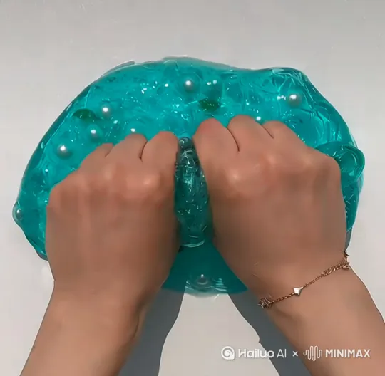 这是一个蓝色的透明泥 里面有薄荷叶子，白色的珍珠，一个人在泥 by Hailuo AI Video Generator